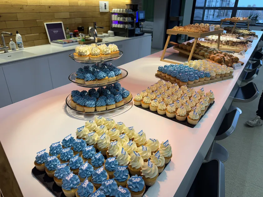 Rautový stůl s chlebíčky a cupcakes v kancelářské kuchyňce